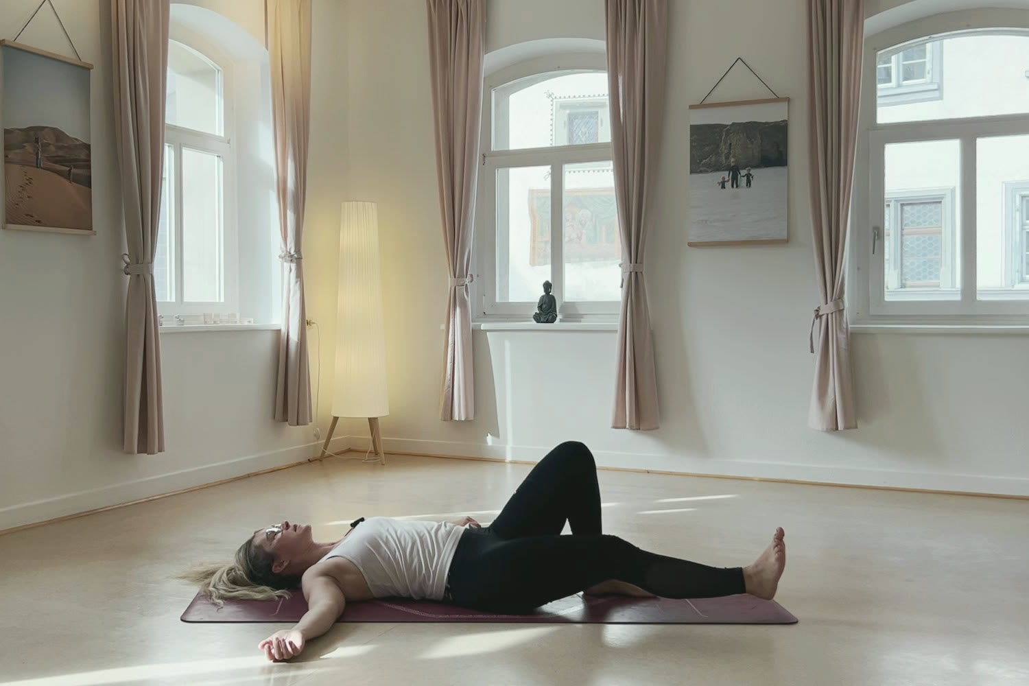 Eli liegt in einer sanften Drehung auf der Yogamatte, Yogastunde in Wangen